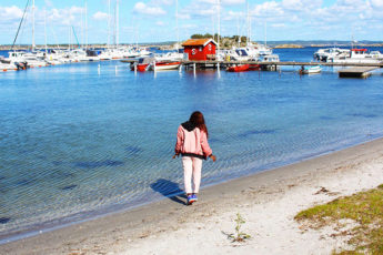 Meltingsisters - a girl dressed in pink standing on the beach in laidback gothenburg