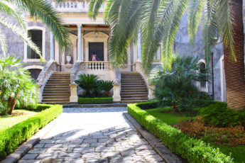 Meltingsisters - the volcanic city of Sicily - palm trees and the entrance to an estate home