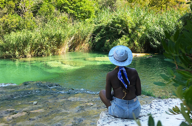 Meltingsisters - Meltingsisters - Sicily’s grand canyon - a black girl sitting on the border of a natural pool