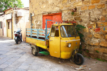 Meltingsisters - Sicily's capital city palermo - a three-wheeled yellow lambretta on a side street